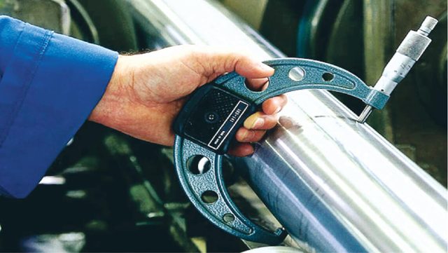 Inspector measuring a stainless steel pipe during visual inspection